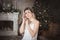 Beautiful young woman in the living room near the Christmas tree. Brooding or lonely, retro style