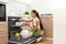 Beautiful young woman loading dishwasher in kitchen.