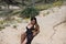 Beautiful young woman with long brown hair in swimming costume and black silk sarong lying on the dunes of the beach posing