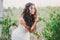 Beautiful young woman with long curly hair dressed in boho style dress posing in a field with dandelions