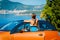 Beautiful young woman with long hair standing back with orange cabriolet at the Mediterranean sea coast