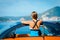 Beautiful young woman with long hair standing back with orange cabriolet at the Mediterranean sea coast