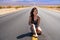 Beautiful young woman with long hair walks along a picturesque empty road in Death Valley overlooking the mountains, USA