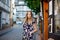 Beautiful young woman with long hairs in summer dress going for a walk in German city. Happy girl enjoying walking in