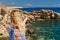 Beautiful young woman is looking to the sea being on the picturesque cliffy coast.