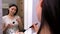 beautiful young woman looks in the mirror, puts powder on her neck with a brush