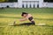 Beautiful young woman lying on a yellow mattress doing pilates or yoga, spin stretch intermediate exercises