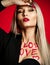 Beautiful young woman makeup artist hold red lipstick rouge with love heart text on body on red