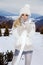 Beautiful young woman in mini dress, standing on the snow and view of the mountains.