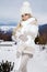 Beautiful young woman in mini dress, standing on the snow and view of the mountains.