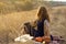 beautiful young woman musician finished playing melody on guitar and relaxing, sitting in field, enjoying autumn sunset.