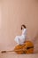 Beautiful young woman musician sitting on a vintage double bass on a beige background