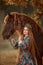 Beautiful young woman in national russian style with red draft horse