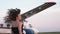 Beautiful young woman next to the plane. Portrait of a beautiful smiling woman in a hat and black dress. young woman in