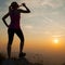 Beautiful young woman observing sunset after running on a mountian