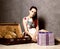 Beautiful young woman packing suitcase and getting ready for traveling, retro concept