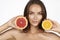 Beautiful young woman with perfect healthy skin and long brown hair day makeup bare shoulders holding orange lemon grapefruit