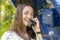 Beautiful young woman in a phone booth. The girl is talking on the phone from the payphone. pretty woman talking by public