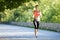 Beautiful young woman in pink top jogging in park