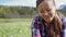 Beautiful young woman in plaid shirt weaves a wreath of meadow dandelion flowers. Portrait of smiling girl.