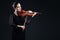 Beautiful young woman playing violin over black