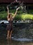 Beautiful young woman plays in creek