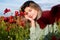 Beautiful young woman in poppy field. Woman on flowering poppy field. Summer holidays on nature. Girl on poppies meadow