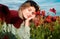 Beautiful young woman in poppy field. Woman on flowering poppy field. Summer holidays on nature. Girl on poppies meadow