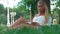 Beautiful young woman portrait reading a book under a tree in the park.