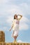 Beautiful young woman poses for photo standing in hay. Blue sky. Summer day. Vertical frame