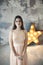 Beautiful young woman posing on gray wall and bright luminous decorative star