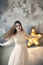 Beautiful young woman posing on gray wall and bright luminous decorative star