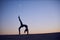 Beautiful young woman practices backbend yoga asana Eka Pada Urdhva Dhanurasana - One Leg Upward facing bow pose in the desert at