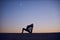 Beautiful young woman practices yoga asana King Pigeon pose rajakapotasana in the desert at night