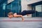 Beautiful young woman practices yoga asana Lotus Peacock Pose - Padma Mayurasana outdoors against the background of a modern city