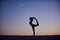 Beautiful young woman practices yoga asana Natarajasana - Lord Of The Dance pose in the desert at night