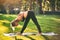 Beautiful young woman practices yoga asana Parsvottanasana - intense side stretch pose in the park at sunset