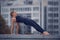 Beautiful young woman practices yoga asana Purvottanasana Upward Plank Pose outdoors against the background of a modern city
