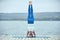 Beautiful young woman practices yoga asana Shirshasana - Headstand pose on the wooden deck near the lake