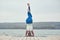 Beautiful young woman practices yoga asana Shirshasana - Headstand pose on the wooden deck near the lake