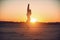 Beautiful young woman practices yoga asana Utkatasana - Chair pose in the desert at sunset