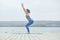 Beautiful young woman practices yoga asana Utkatasana - Chair pose on the wooden deck near the lake