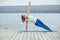 Beautiful young woman practices yoga asana Vasishthasana - side plank pose on the wooden deck near the lake