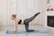 Beautiful young woman practicing yoga stretching at home on mat