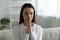 Beautiful young woman praying seated on couch in living room