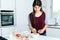 Beautiful young woman preparing cereal bowls in the kitchen.