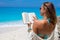 Beautiful young woman reading a book on the beach