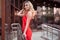 Beautiful young woman in a red dress on the stairs in front of the store