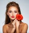 Beautiful young woman with a red flower in hand near face.  Portrait of a  girl with red rose in hands