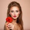 Beautiful young woman with a red flower in hand near face.  Portrait of a  girl with red rose in hands